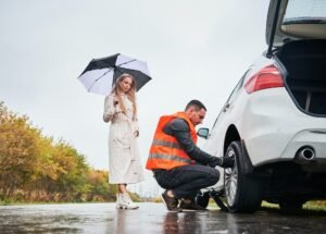 Emergency auto mechanic changing flat tire on woman car.
